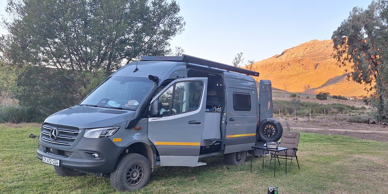 Outdoor living setup with an awning, camping chairs, and a braai kit.